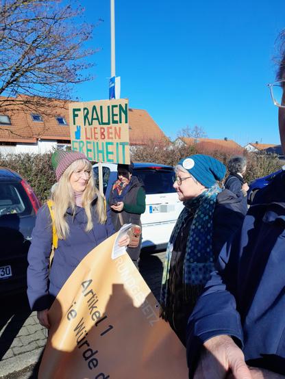 Demo-Teilnehmende mit einem Plakat "Frauen-Lieben-Freiheit"